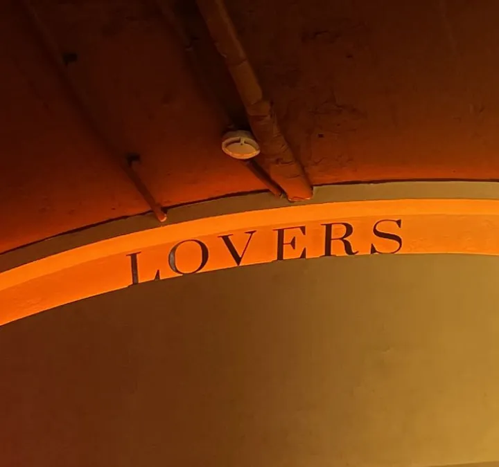 Illuminated archway with LOVERS lettering glowing in warm orange light