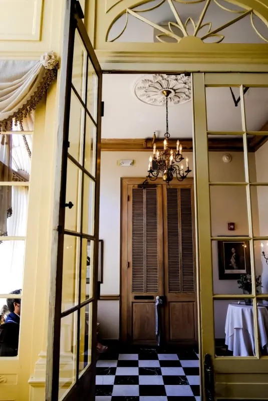 Yellow-framed venue doorway opening onto a black-and-white checkered floor and chandelier