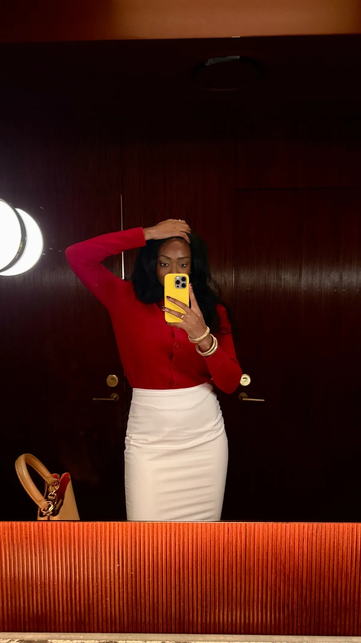 Kimi, founder of The Binder Co., in a red top and white skirt taking a mirror photo