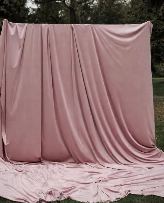 Dusty rose velvet drapery backdrop set up outdoors on grass