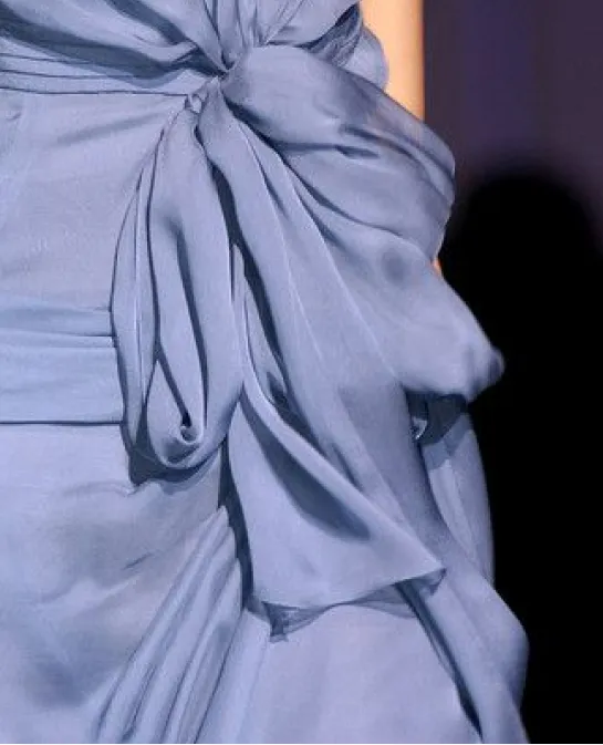 Close-up of a draped dusty blue silk gown with a bow detail